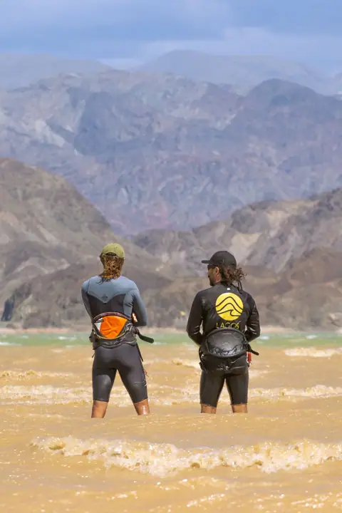 Instructor y alumna con indumentaria de Lagos Kite Surfing frente al agua
